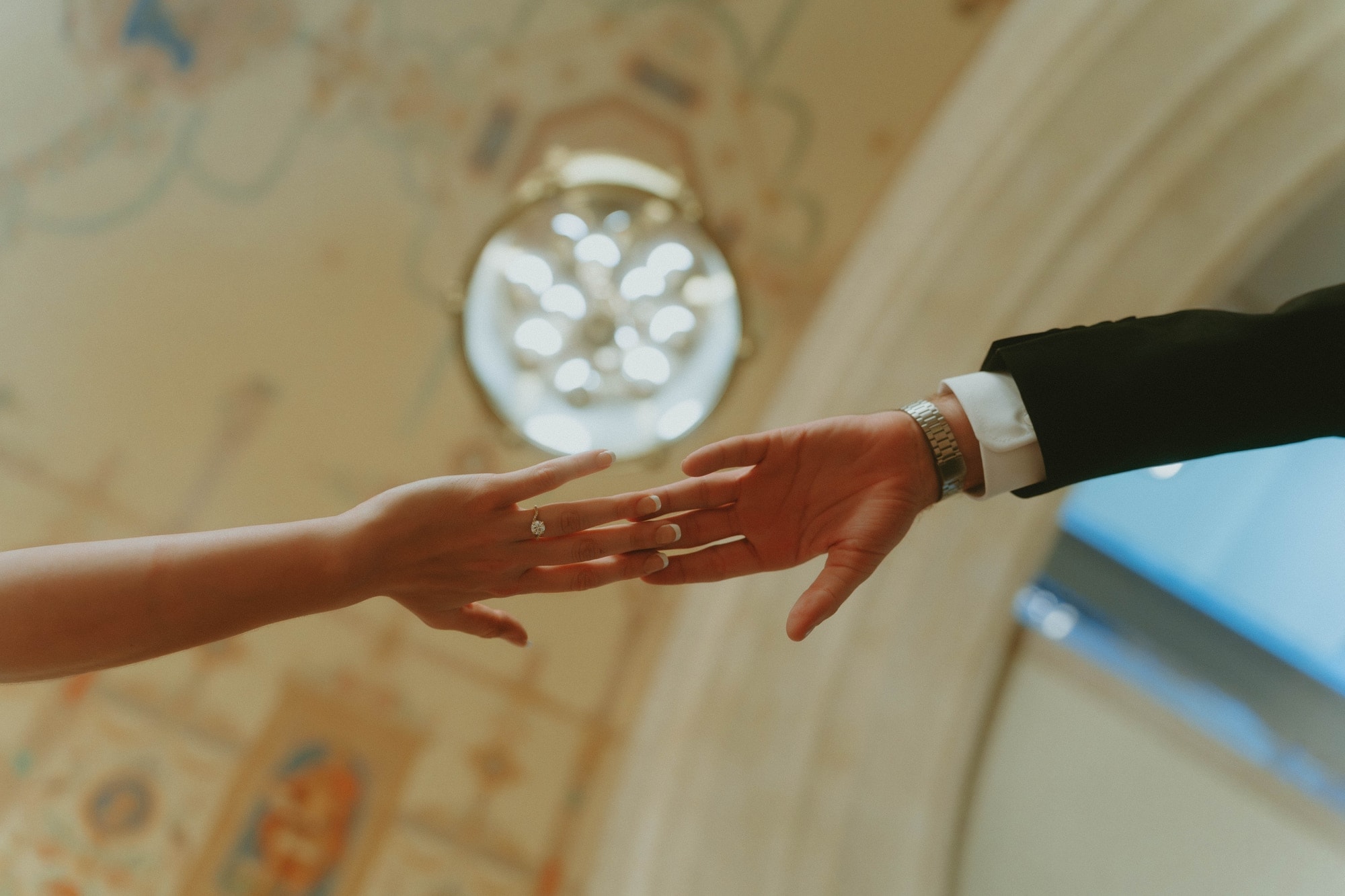 Tylar and Carly's hands reaching toward each other, wearing their engagement rings