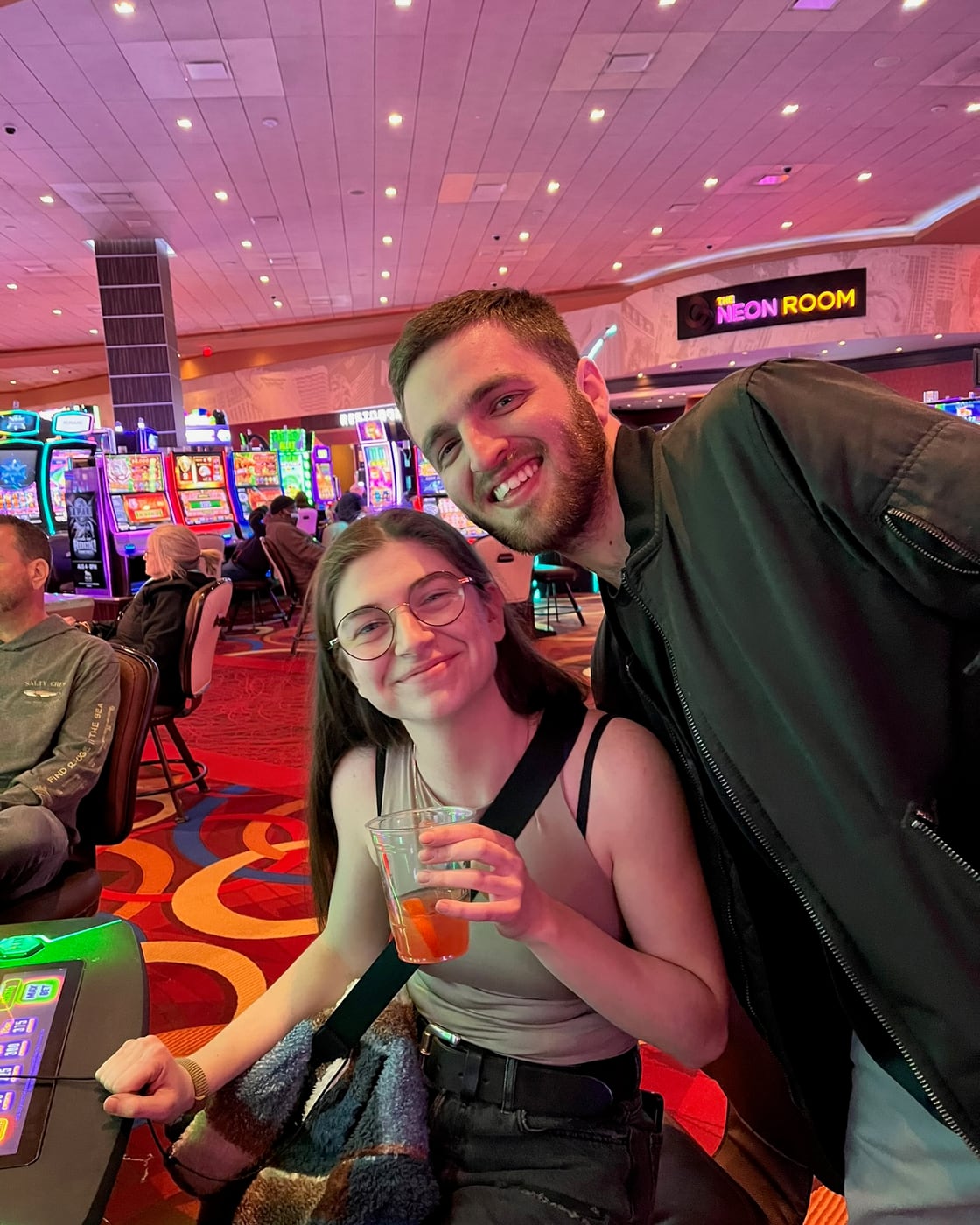 Tylar and Carly with drinks in a brightly lit arcade