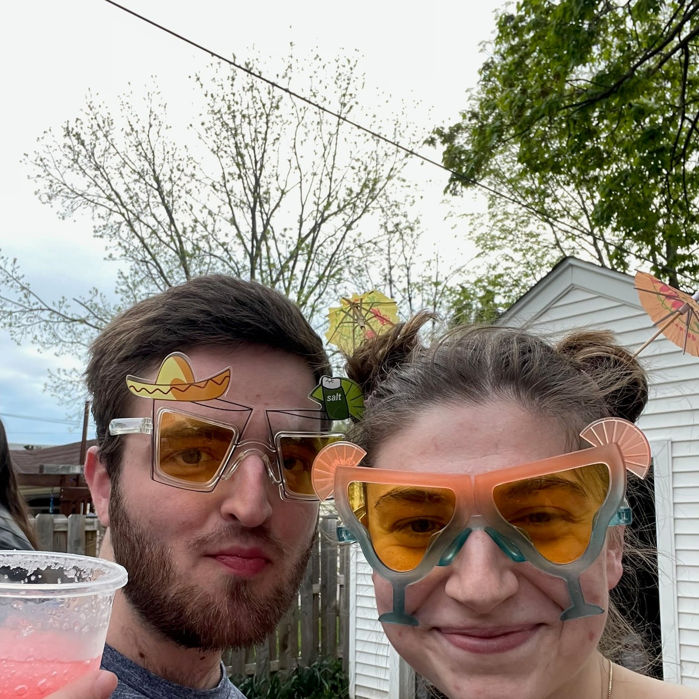 Tylar and Carly in novelty sunglasses with drinks in the backyard