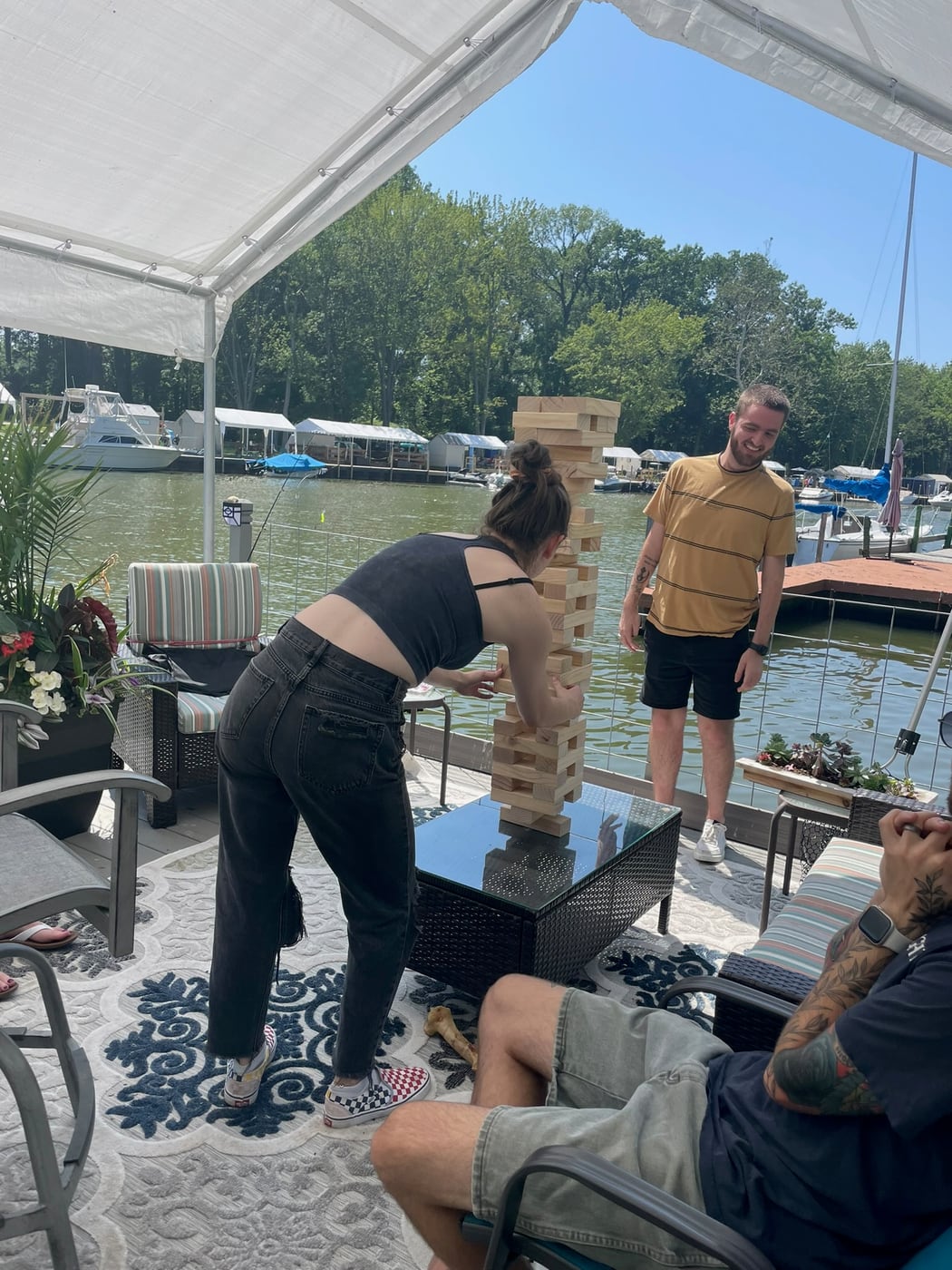 Tylar and Carly playing a stacking game under a canopy at the lake