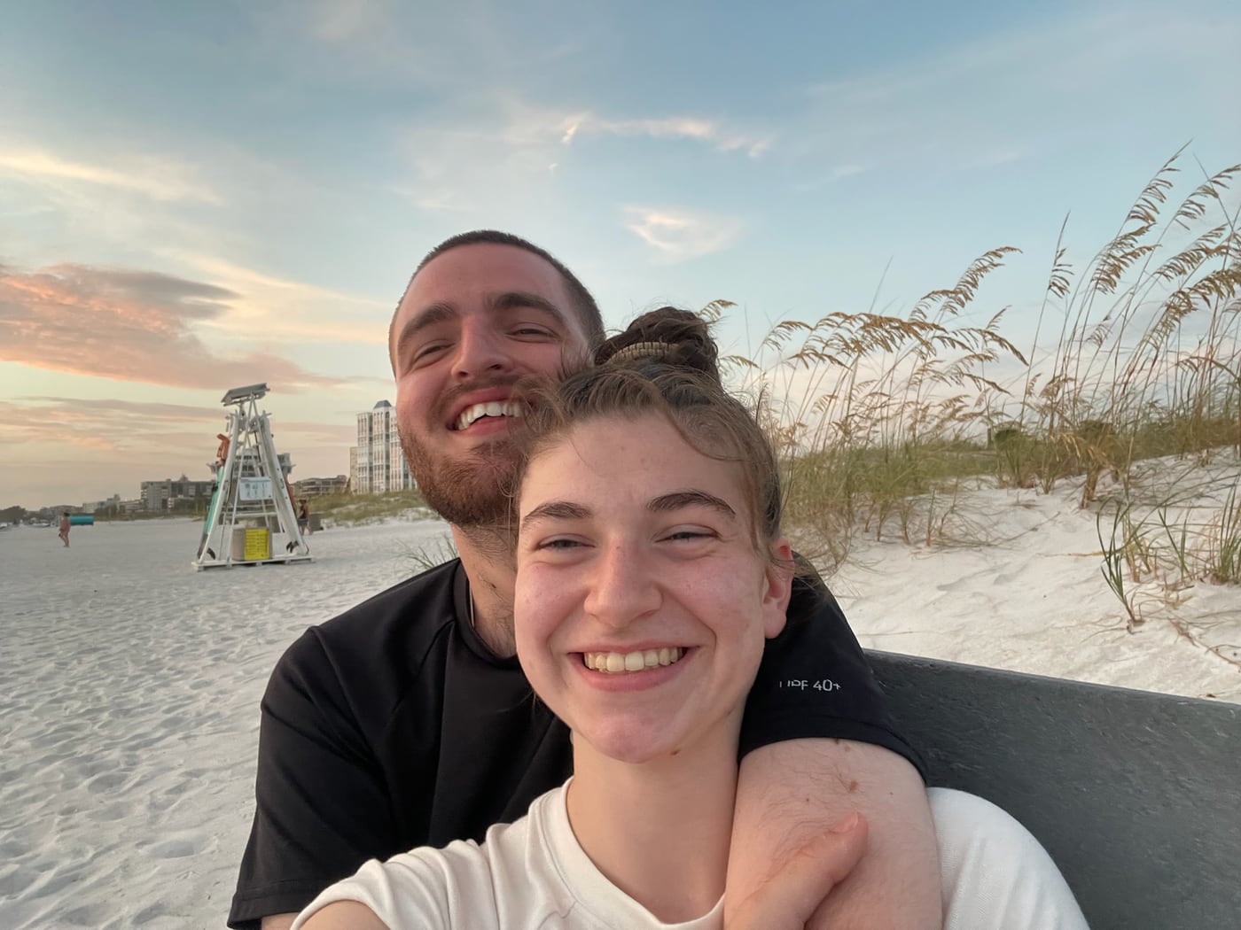 Tylar and Carly on the beach at sunset, sea oats behind them