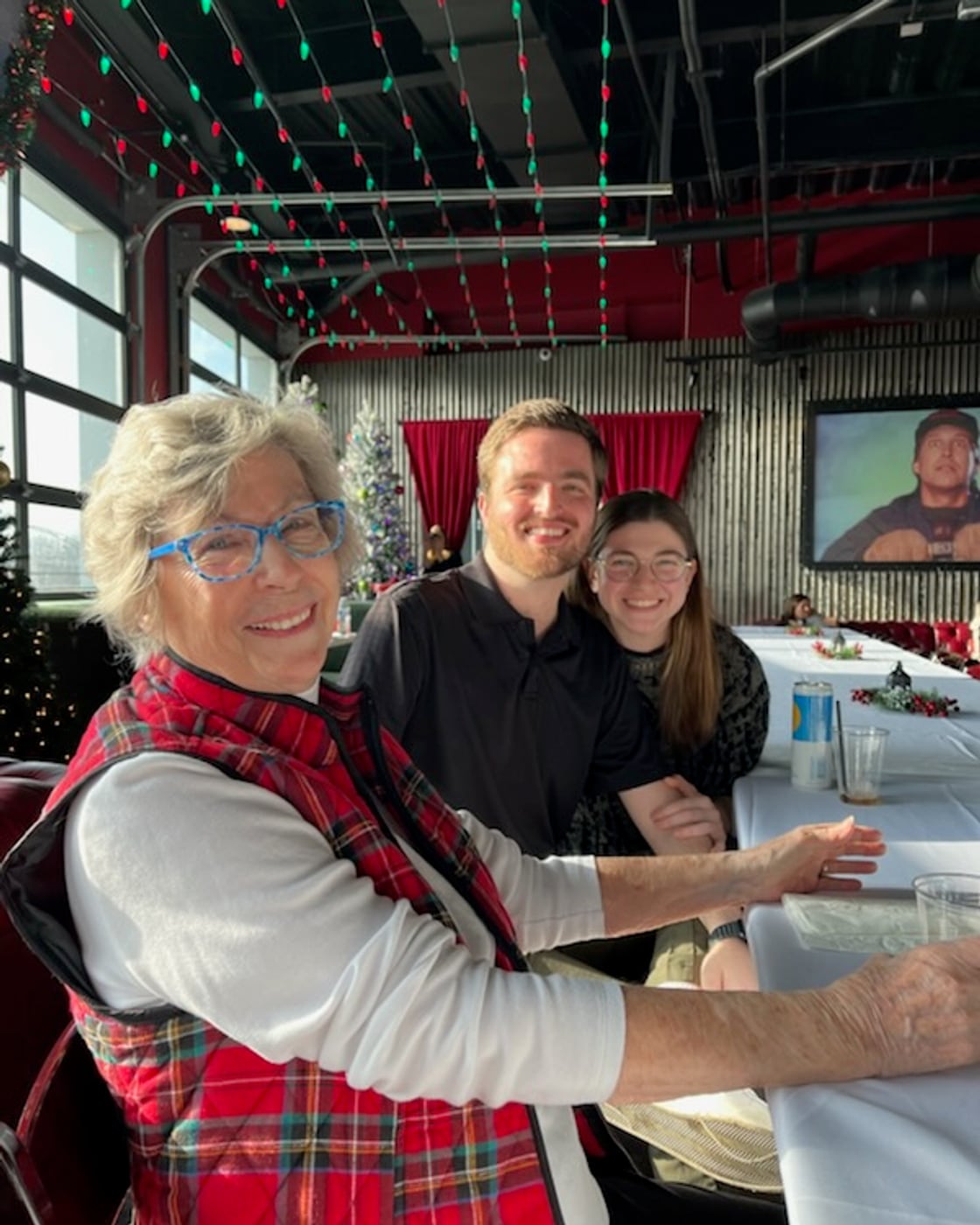 Tylar and Carly with a grandmother at a restaurant decorated for Christmas