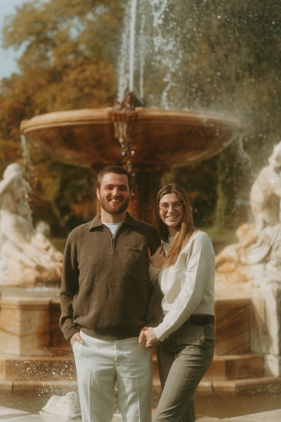 Tylar and Carly standing together before an ornate stone fountain
