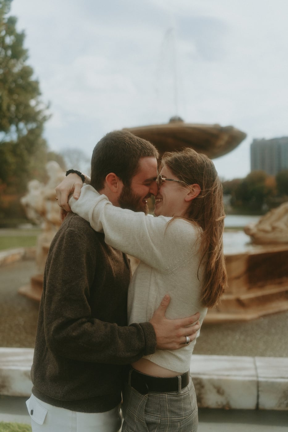 Tylar and Carly holding each other close beside a stone fountain
