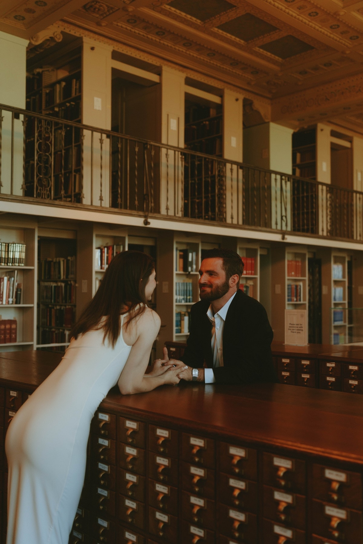 Tylar and Carly leaning together over a library card catalog