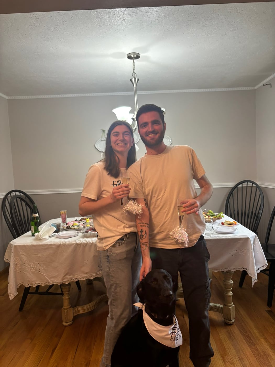 Tylar and Carly at home beside a table set for two, their dog underfoot