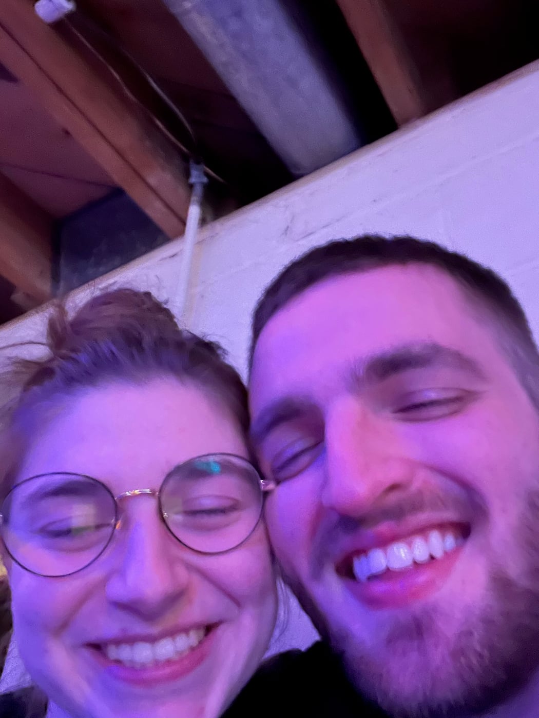 Tylar and Carly laughing close together under violet light