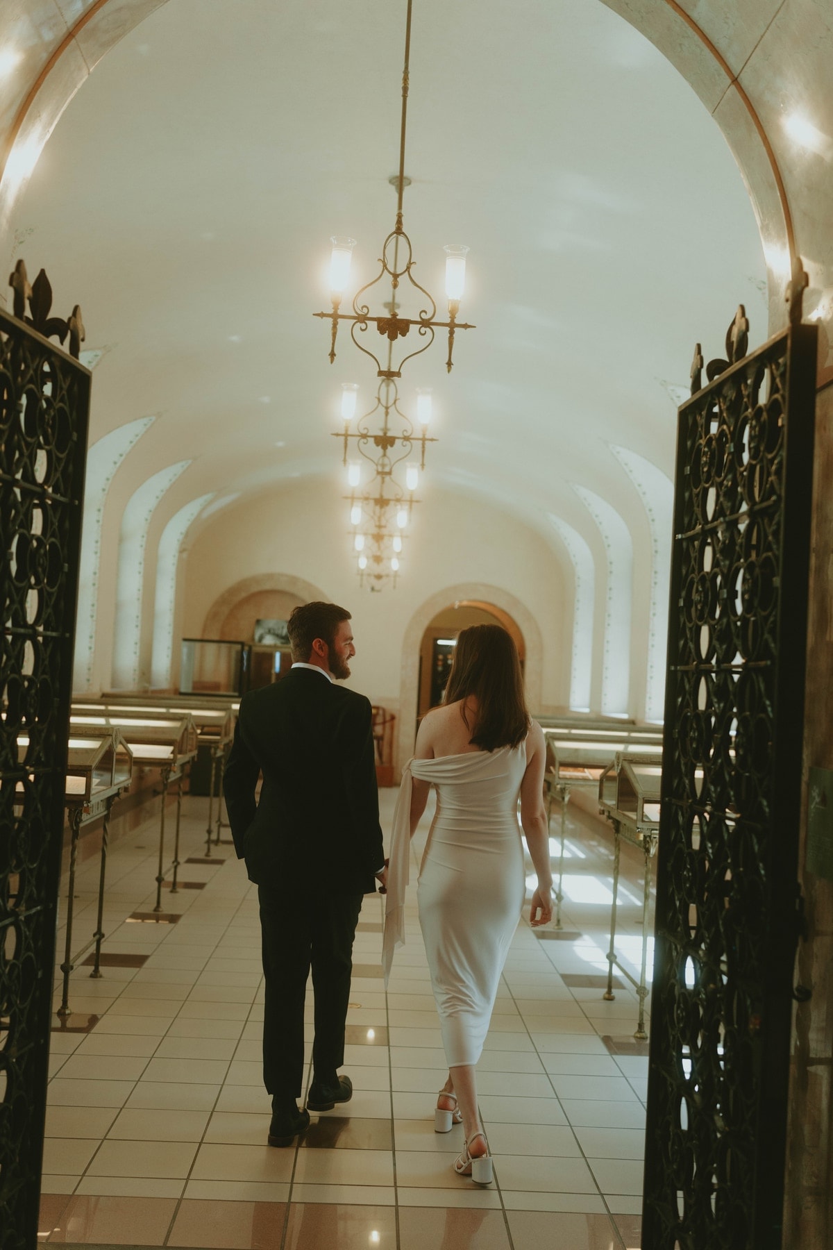 Tylar and Carly walking hand in hand away through ornate iron gates