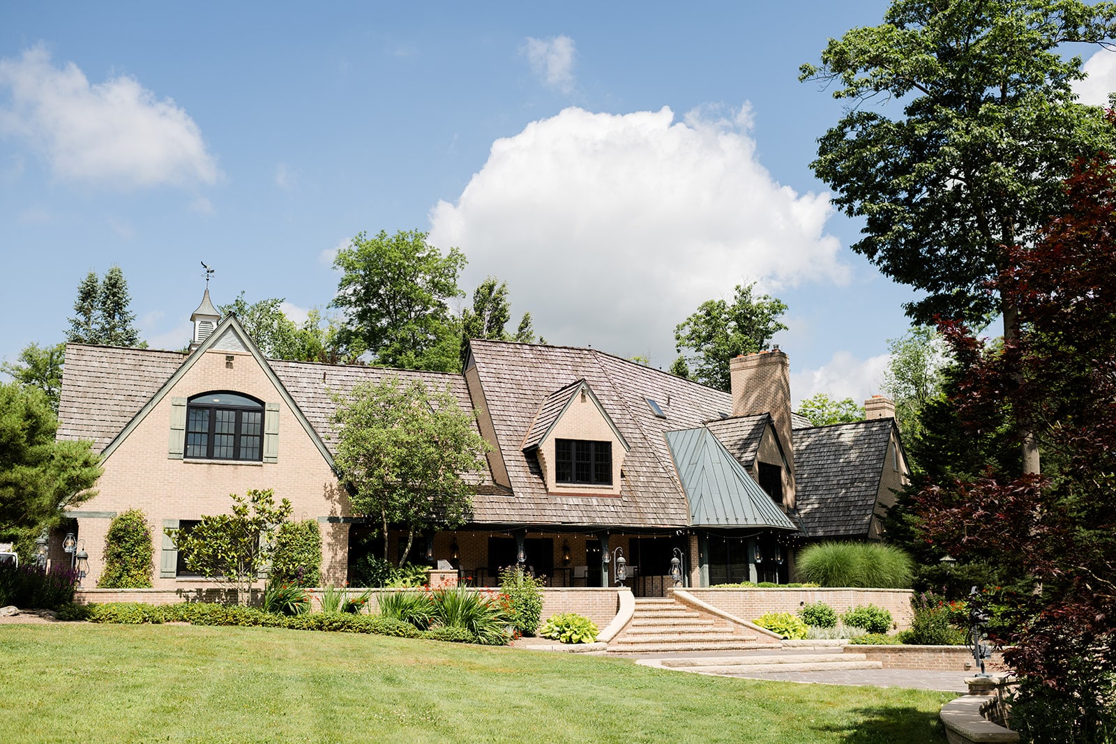 The manor house in summer, framed by lawn and old trees