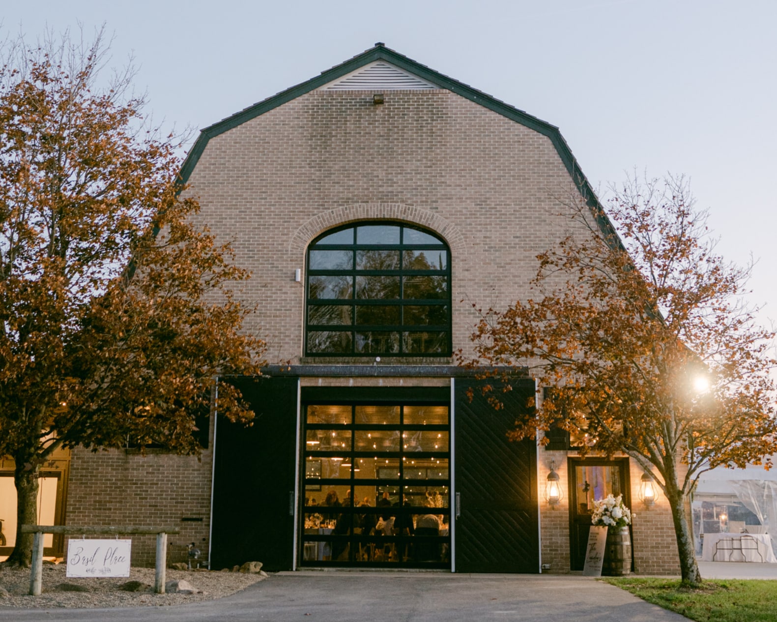 The carriage barn at dusk, its doors glowing from within